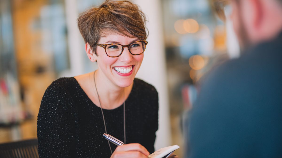 Coach die enthousiast notities maakt tijdens een gesprek met een klant