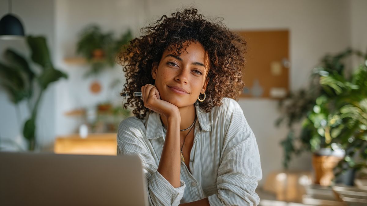 Coach die ontspannen achter haar laptop werkt aan social media content in een licht kantoor